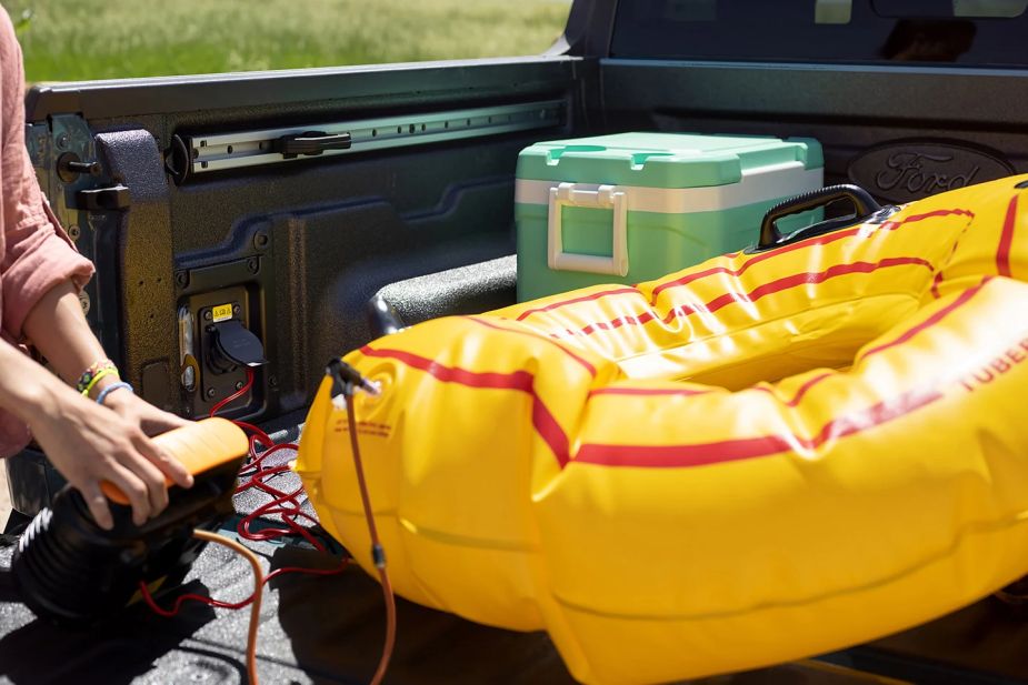 A 2022 Ford Maverick owner inflates a floatation device using a truck-bed outlet, essential for tailgating. 