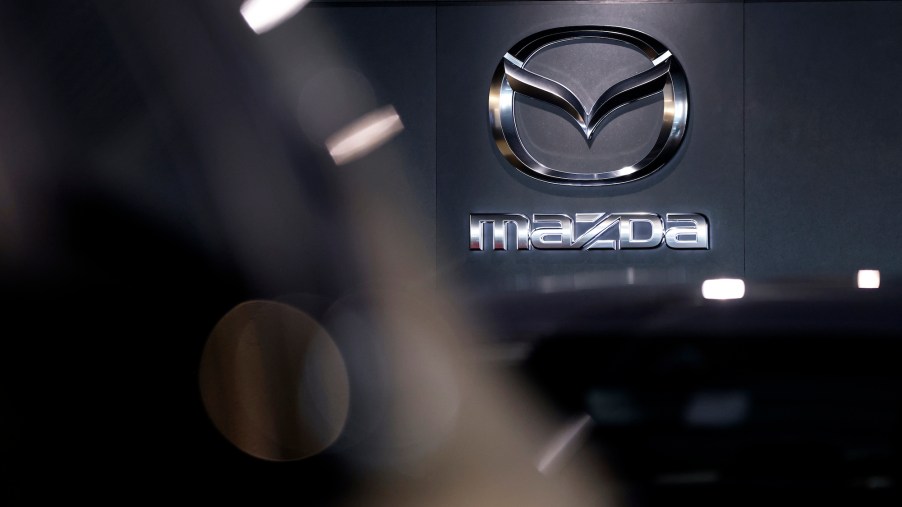 A Mazda logo, maker of the Mazda CX-50, on a black wall.