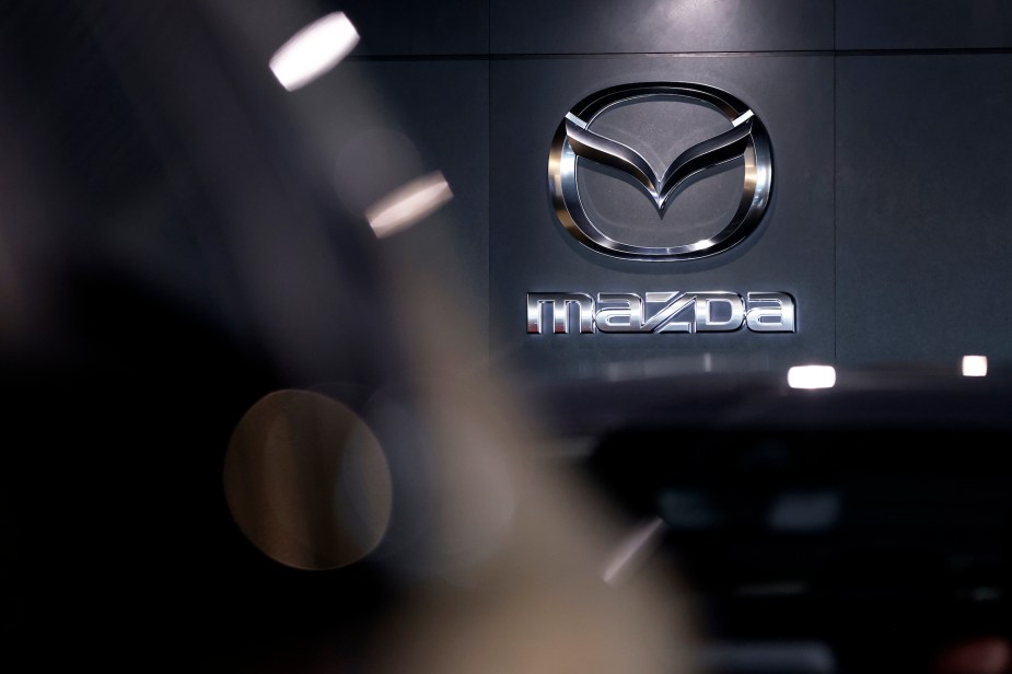 A Mazda logo, maker of the Mazda CX-50, on a black wall. 