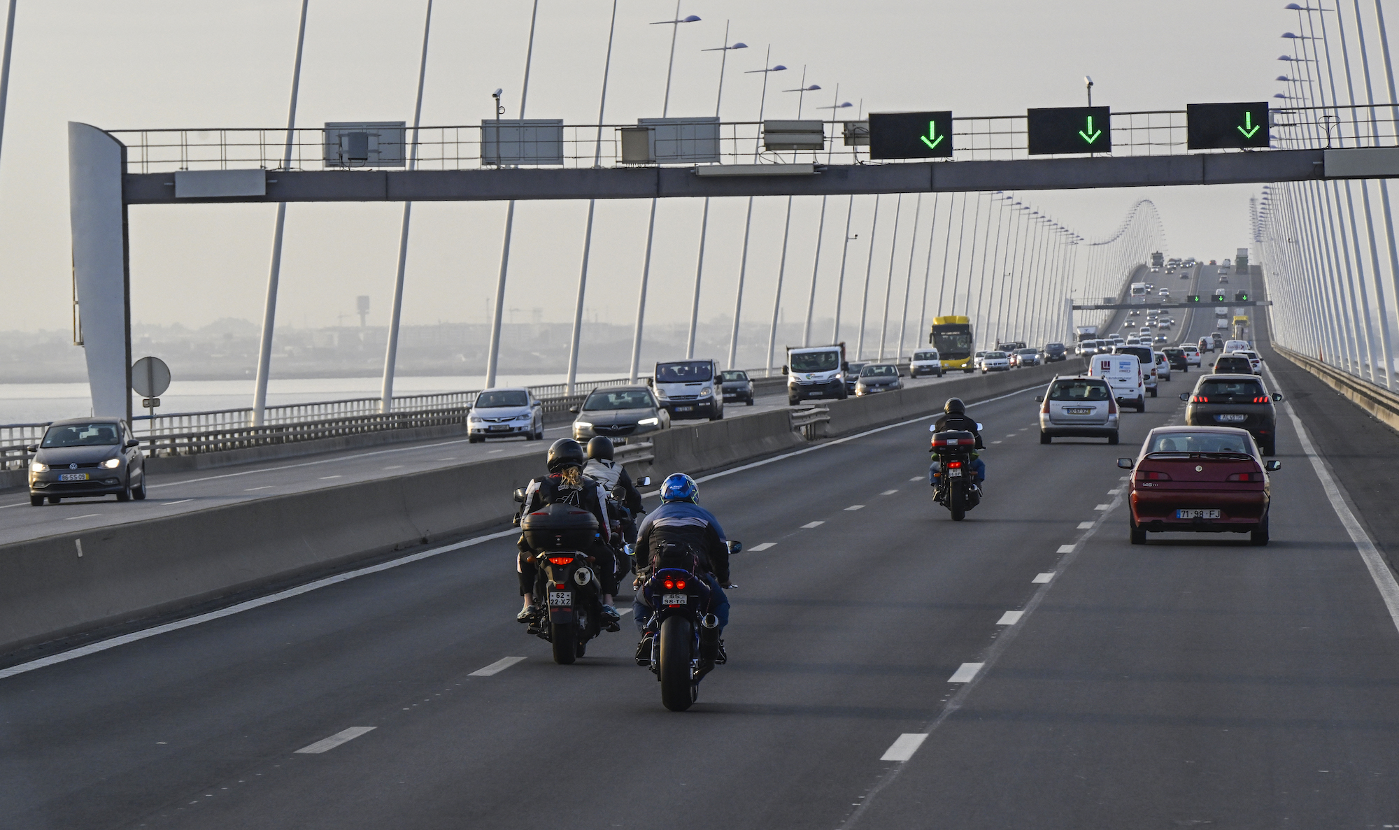 People riding a motorcycle in high winds potentially across a bridge.