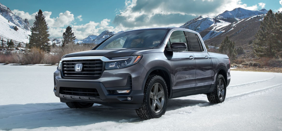 Honda's mid-size truck, the 2023 Ridgeline sits in the snow with mountains behind it.