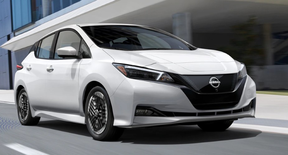 A white 2022 Nissan Leaf electric hatchback is driving on the road. 