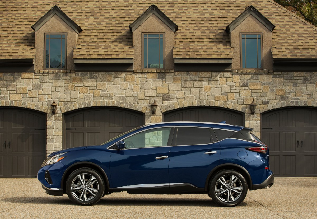 A blue 2023 Nissan Murano parked in front of a four car garage