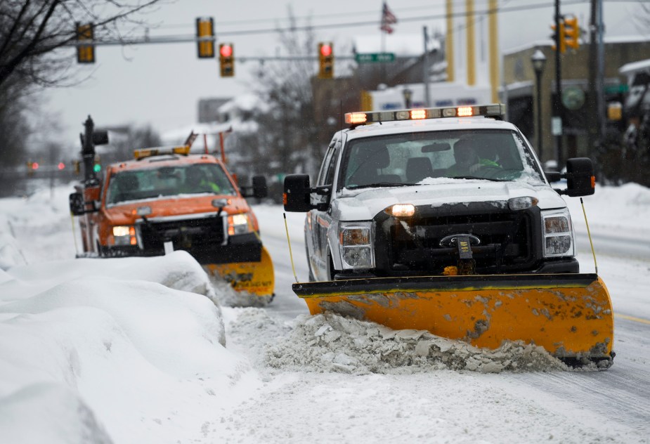 Plow trucks with yellow or amber flashing marker lights on their roof tops for visibility.
