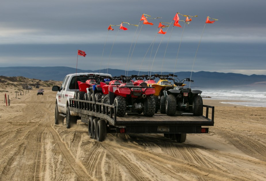 A truck tows a trailer full of ATVs down Pismo Beach and to Oceano Dunes OHV park.
