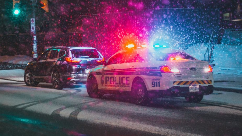Traffic police car stops on snowy road, highlighting why cops touch the rear of cars during traffic stops