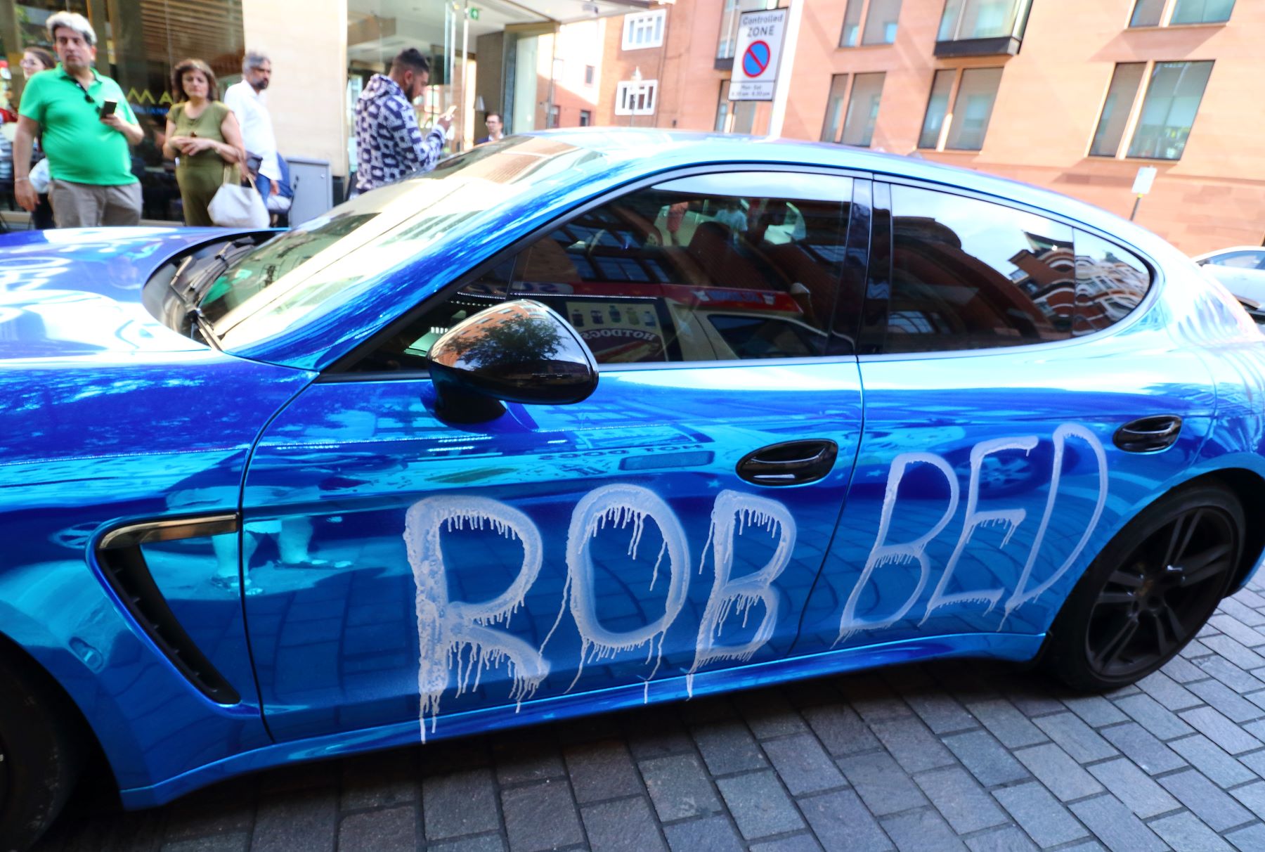 Vandalism spray paint on a blue model Porsche supercar in London, UK
