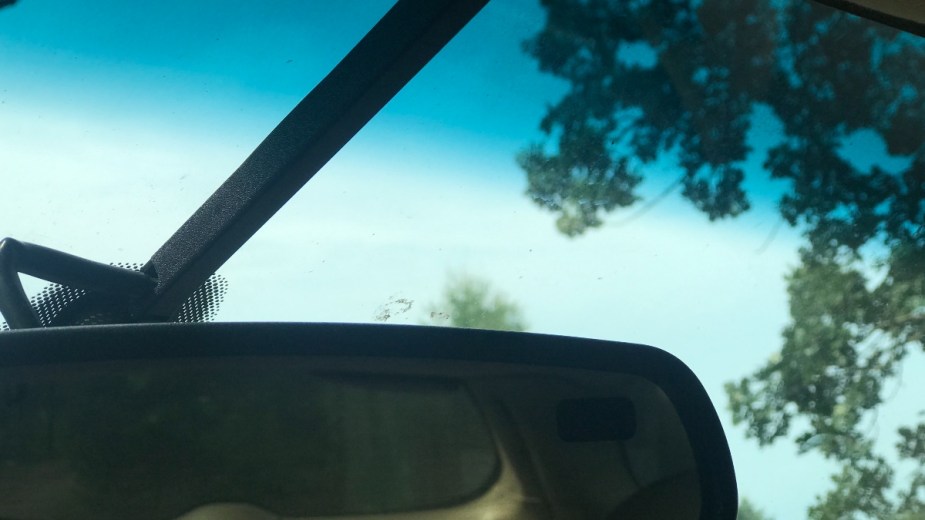 Rearview mirror and blue-green color tinting at the top of a car windshield