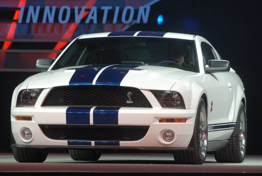 An S197 Ford Mustang Shelby GT500 with blue stripes shows off its front-end styling at a car show.
