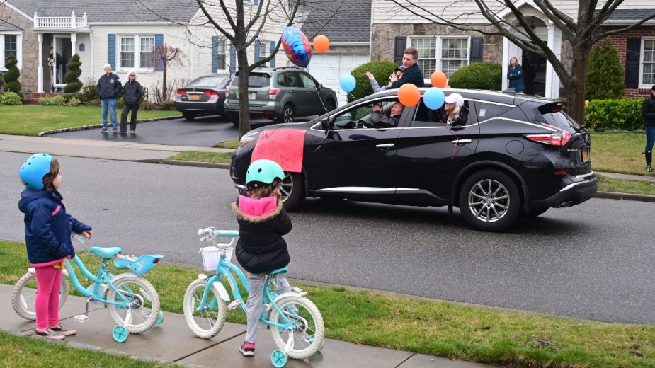 SUV driving by children holding signs, highlighting ways to slow down traffic in your neighborhood
