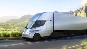 A silver Tesla Semi truck driving down a mountainous road.