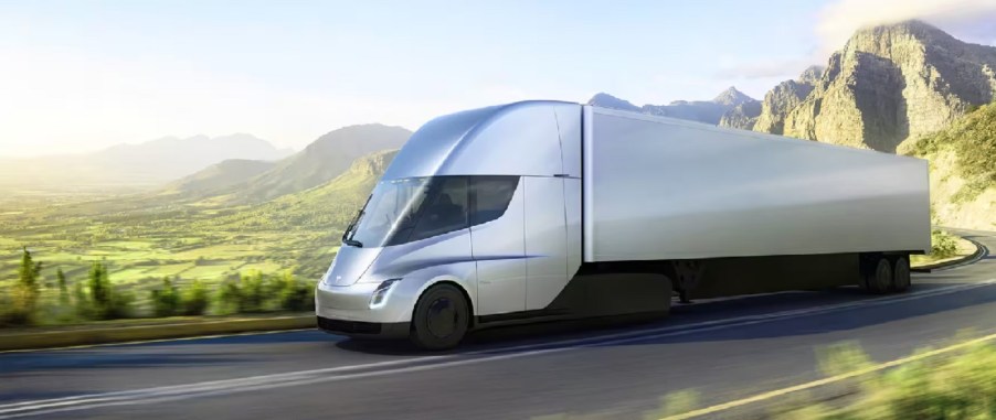 A silver Tesla Semi truck driving down a mountainous road.