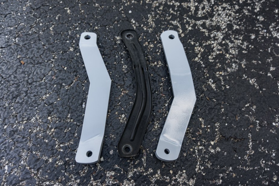 A 2013 Fiat 500 Abarth's stock black front subframe chassis brace between two gray El Gato Engineering braces