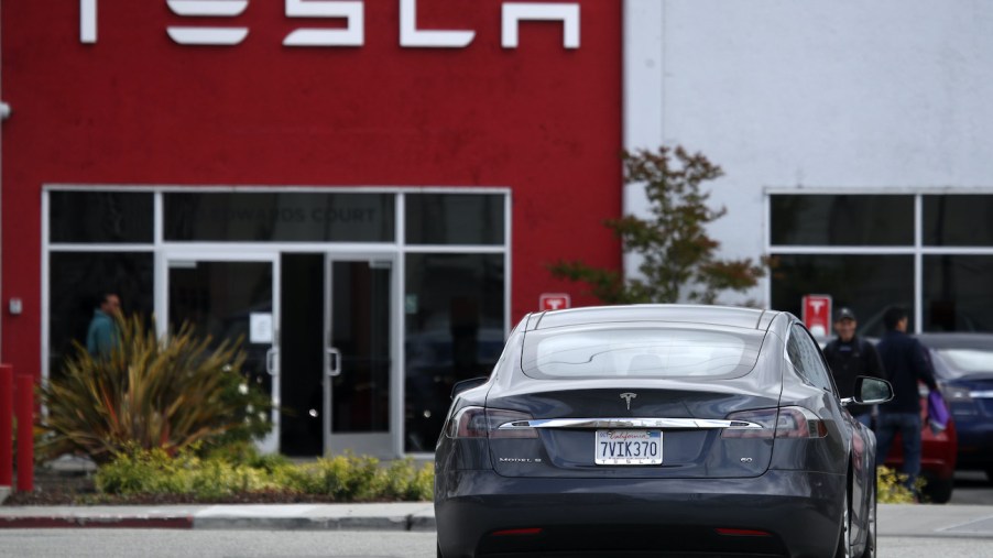 A Tesla Model S drives into the parking lot of a Tesla showroom.