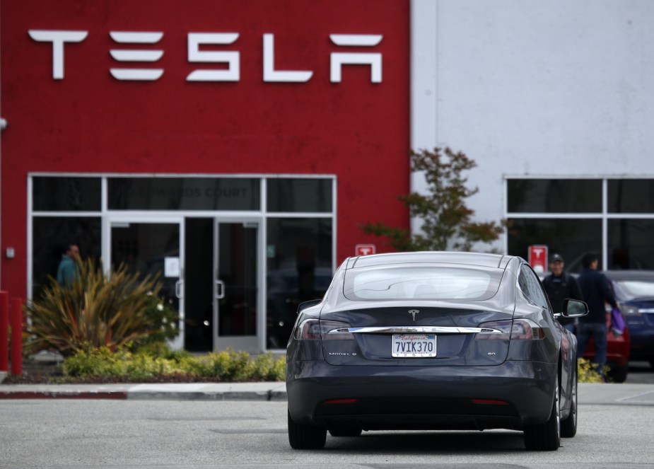 A Tesla Model S drives into the parking lot of a Tesla showroom.