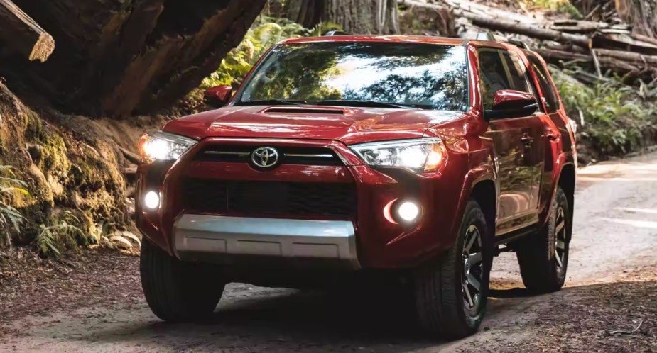 A red Toyota 4Runner midsize SUV is driving on the road. 