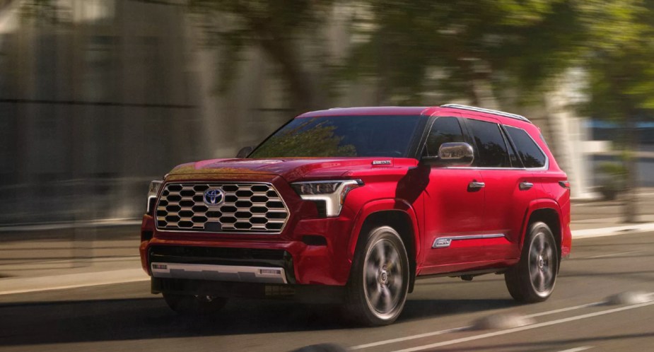 A red 2023 Toyota Sequoia is driving on the road. Experts don't recommend the most popular trim level. 