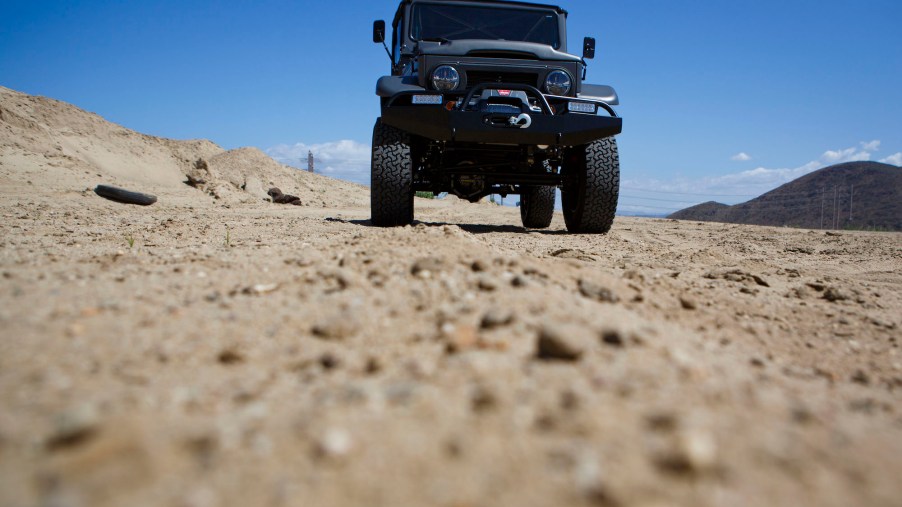 A black Toyota Land Cruiser FJ40 in a dry desert-like area.