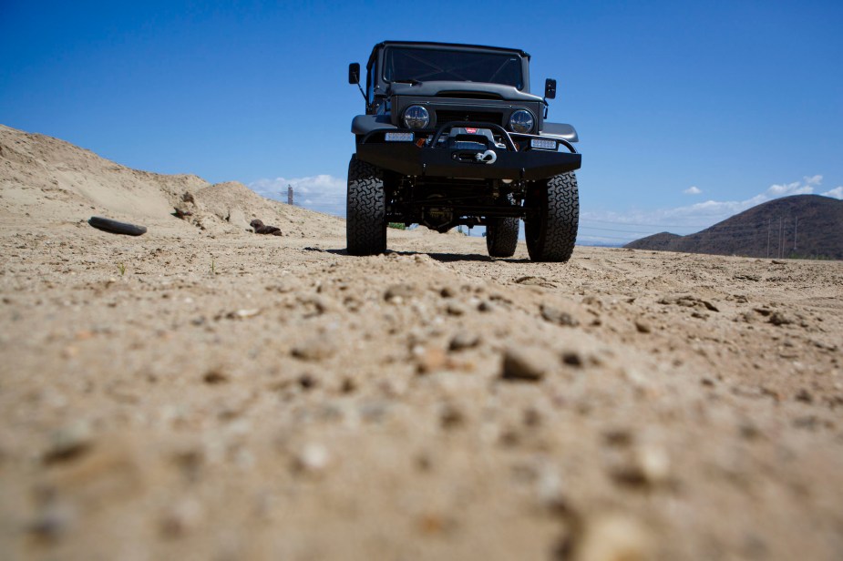 A black Toyota Land Cruiser FJ40 in a dry desert-like area.