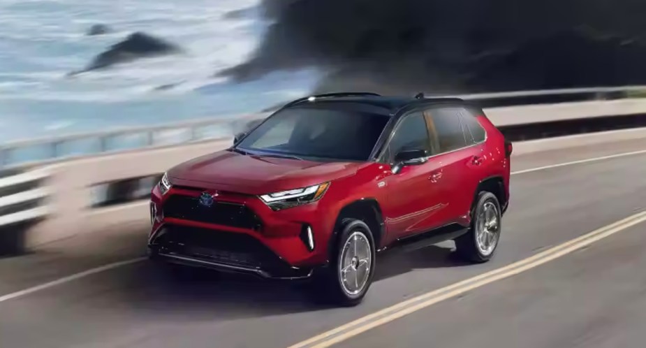 A red Toyota RAV4 Prime is driving on the road. 