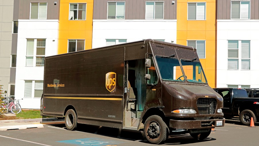 A brown UPS delivery truck sits in a parking lot.