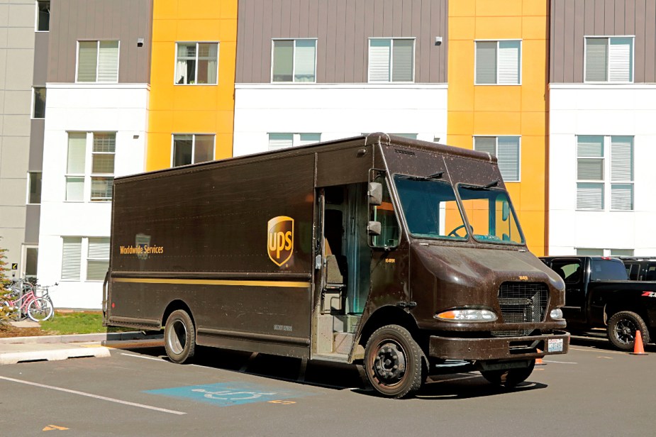 A brown UPS delivery truck sits in a parking lot.