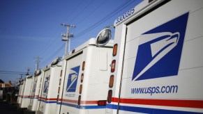 A group of USPS mail trucks sit parked.