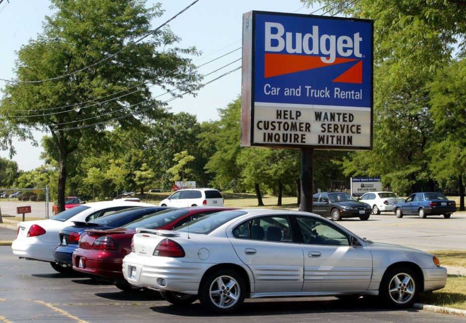 Vehicles parked in a Budget Car and Truck Rental parking lot, highlighting ways to pay less on car rental rates