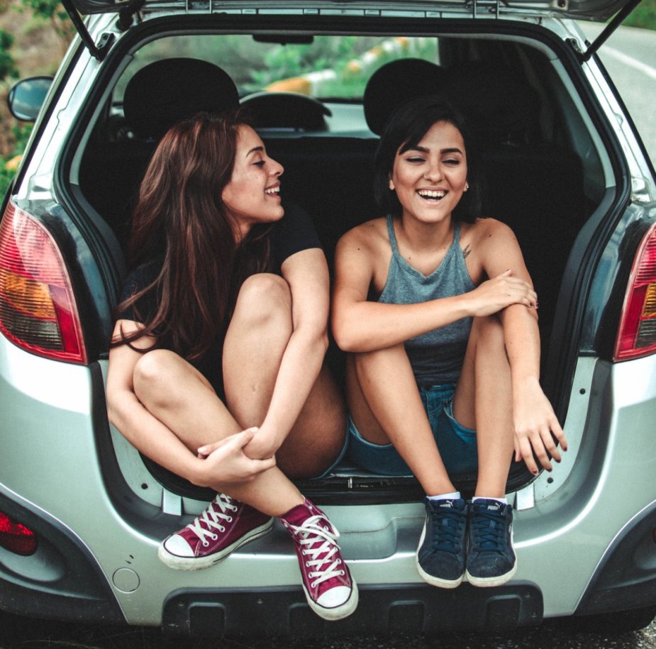 Women sitting near the car's cargo area, pointing out how a car is the best place for difficult conversations