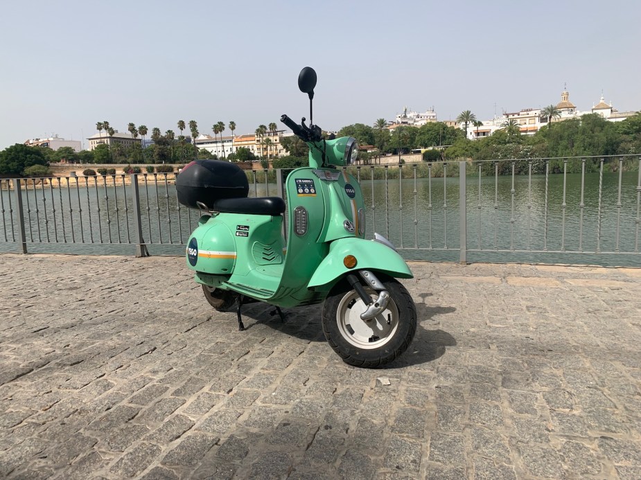 Closeup of a YEGO rental scooter parked in front of the Spanish city of Sevilla.