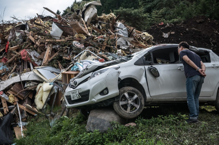 A man peers inside a destroyed car after an earthquake.