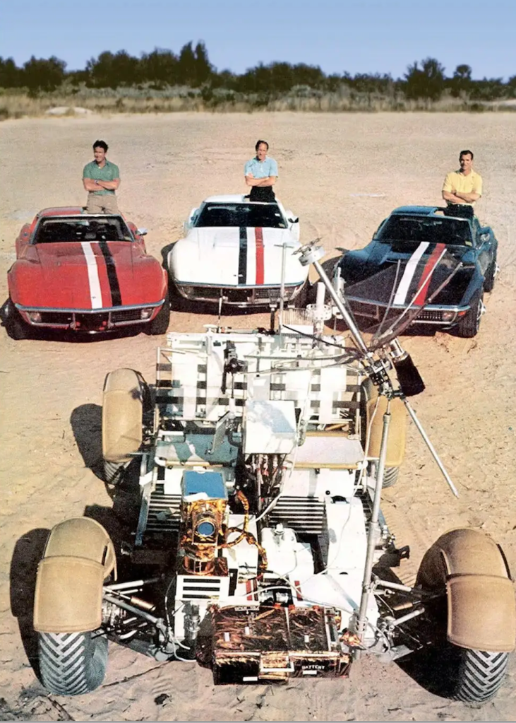 Three astronauts standing behind their Chevrolet Corvettes 