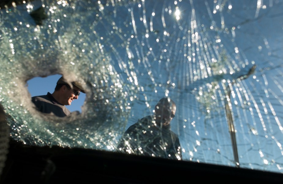Cops look at a shattered glass window.