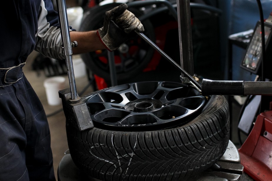 A car tire being installed on a giant rim. DO you have to replace all four tires?