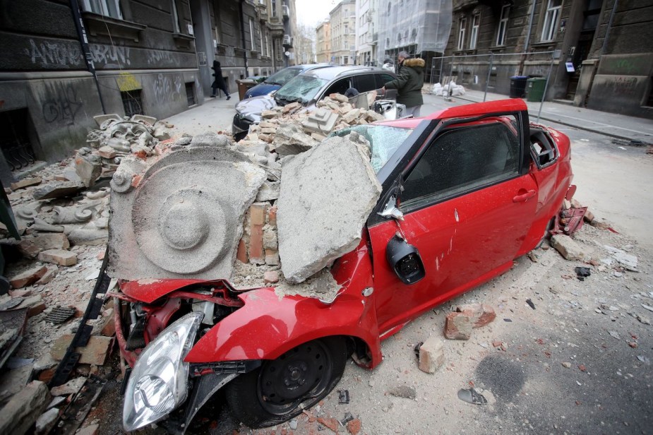 A car destroyed by building rubble after an earthquake