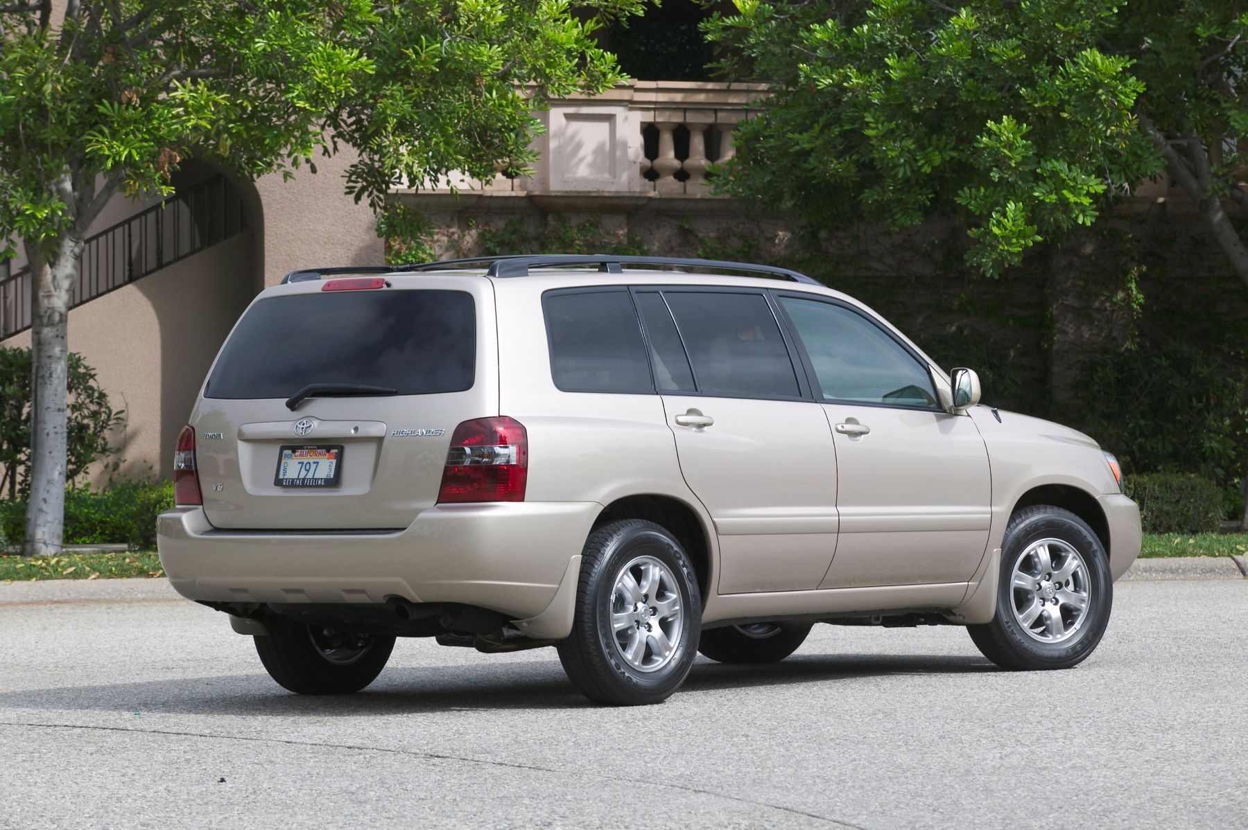 A beige 2004-2007 Toyota Highlander midsize SUV generation model parked on an asphalt suburban street