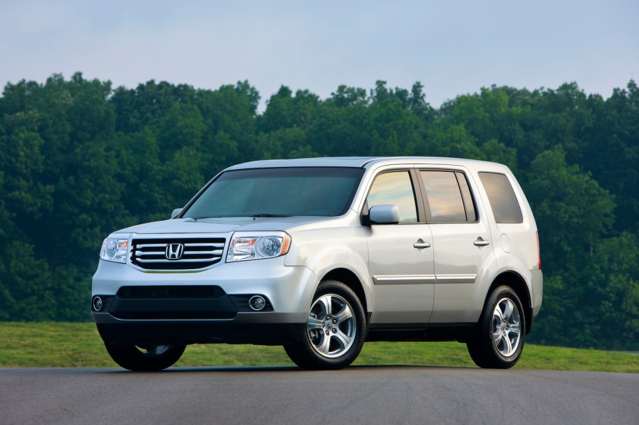 A silver 2015 Honda Pilot parked in front of trees, the Pilot is one the safest used SUVs for teens