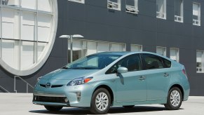 A light green 2015 Toyota Prius Plug-in parked in front of a building