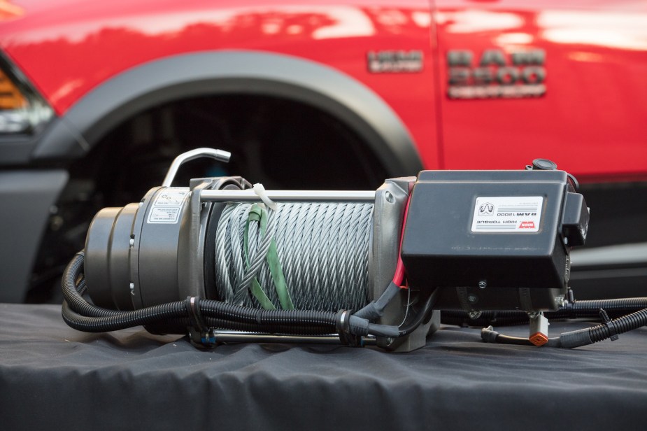 Closeup of a Warn 12 winch in front of a red Ram 2500 Power Wagon 4x4 pickup truck.