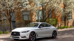 A white 2022 Infiniti Q60 luxury sports coupe model parked on a cobblestone street
