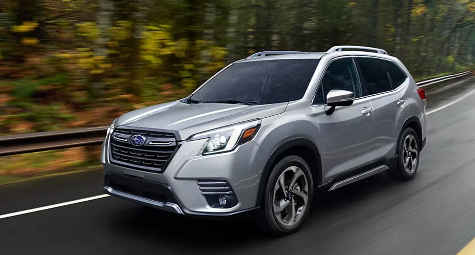 A gray 2022 Subaru Forester small SUV is driving on the road. 