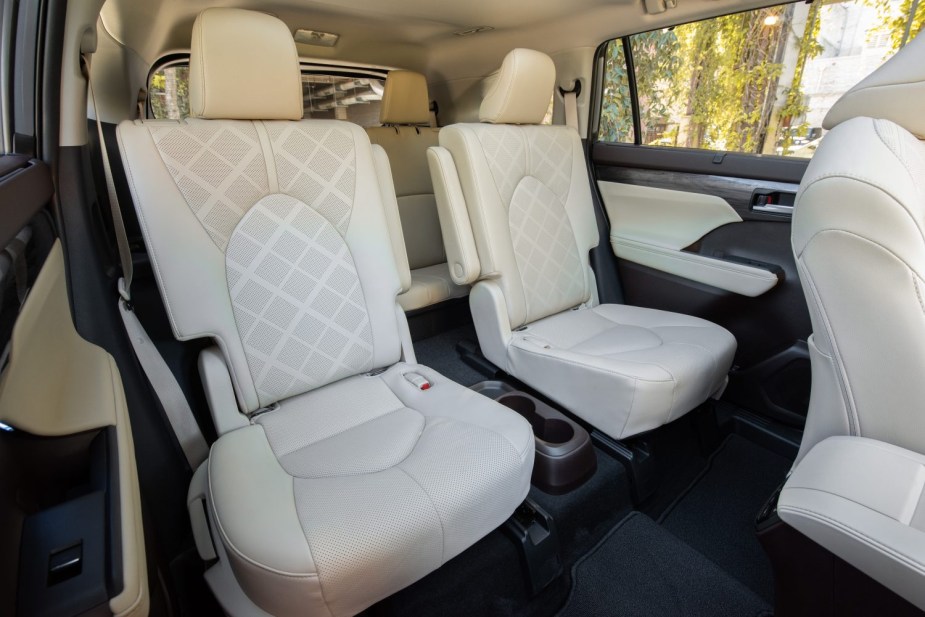 The spacious interior of a large Toyota Highlander third-row hybrid SUV in white leather.