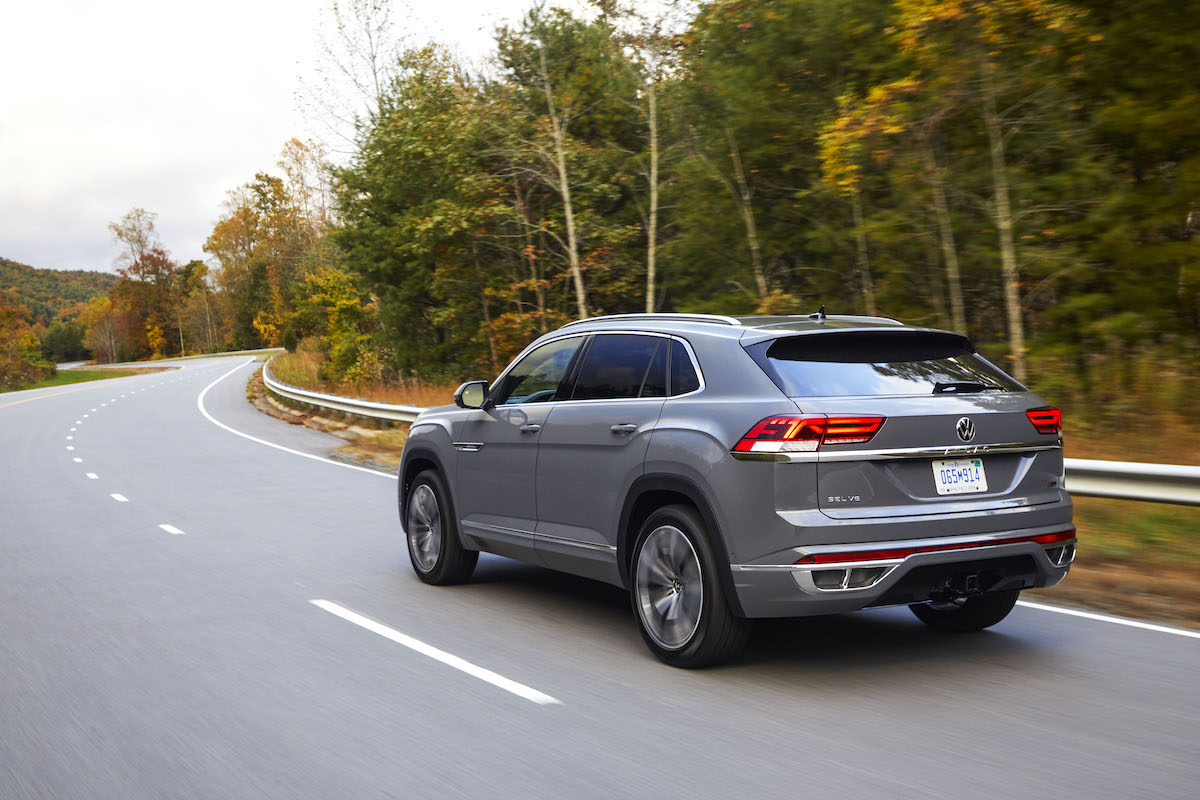 A silver 2022 Volkswagen Atlas Cross Sport driving down the highway in a wooded area.