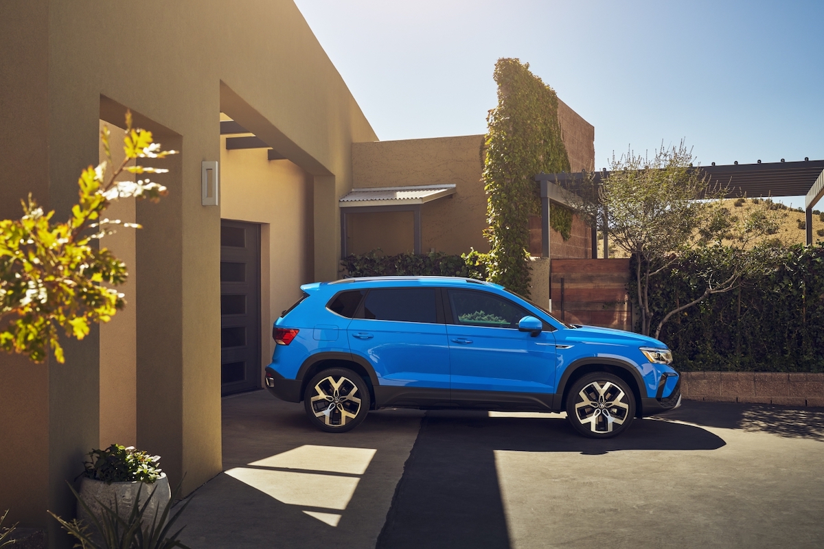 A blue 2023 Volkswagen Taos parked in front of a building.