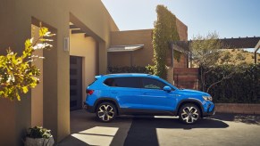 A blue 2023 Volkswagen Taos parked in front of a building.