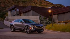 A 2023 Cadillac Lyriq luxury electric SUV parked outside a luxury home under a lamp post/streetlight