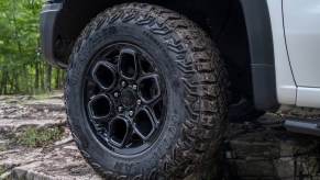 Closeup of the forged rim of a 2023 Chevrolet Silverado pickup truck with an off-road package, trees visible in the background.