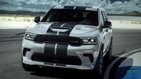 A 2023 Dodge Durango midsize SUV with a hood vent and racing stripe on a racetrack