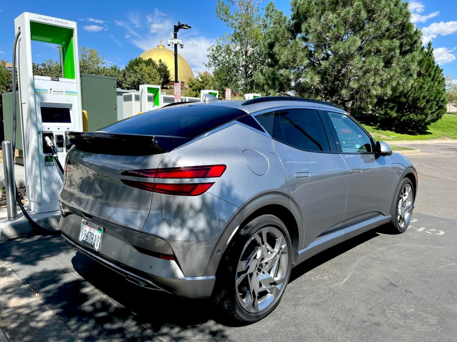 A rear view of the 2023 GV60 next to a charger.