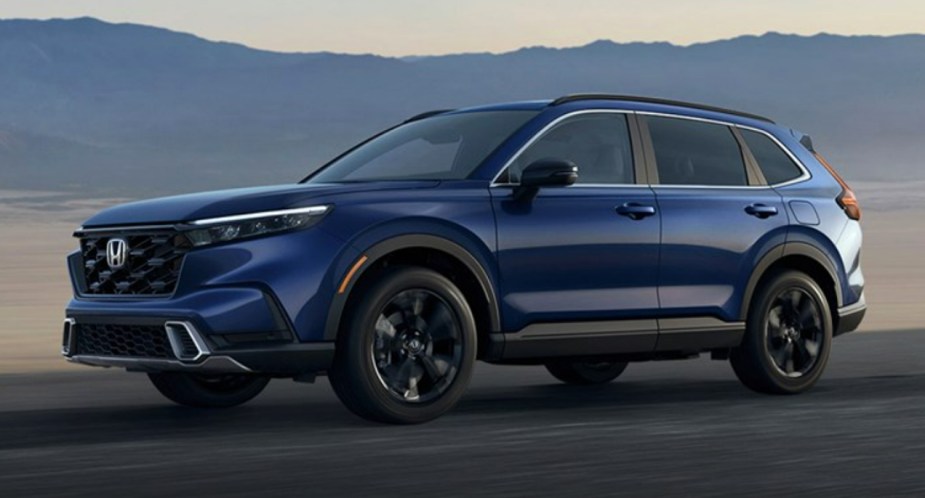 A blue 2023 Honda CR-V Hybrid small SUV is driving on the road.